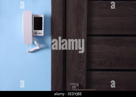 Modern intercom system with handset on light blue wall indoors Stock Photo