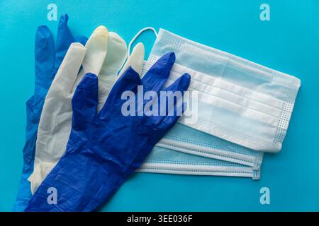 Assortment of medical PPE including blue and white gloves with surgical masks on a blue background Stock Photo