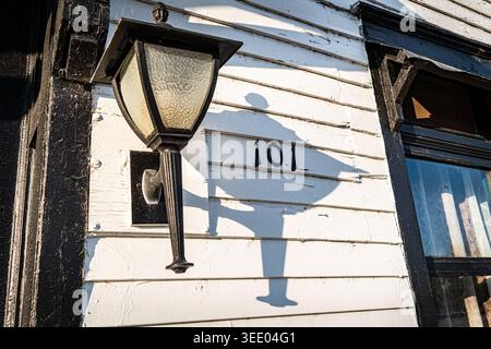 This photograph features a vintage-style black lantern mounted on a white, weathered clapboard wall. Stock Photo