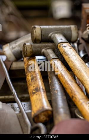Workshop tools, including rubber mallets and various metal drill bits, lying in a close up angle, representing craftsmanship, manual labor, and the pr Stock Photo