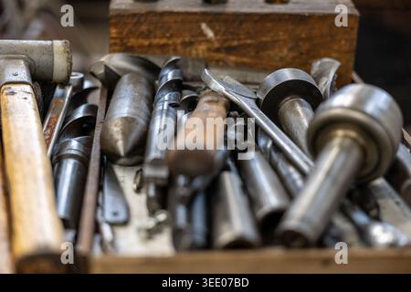 Workshop tools, including rubber mallets and various metal drill bits, lying in a close up angle, representing craftsmanship, manual labor, and the pr Stock Photo