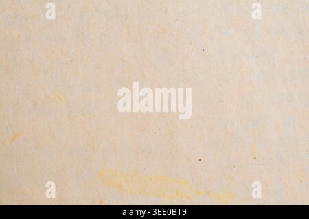 Close-up view of a light beige textured paper surface showing natural imperfections like small dark specks and organic yellow discoloration Stock Photo