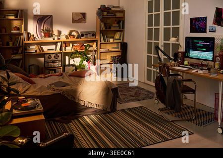 Wide angle shot of home music studio bedroom featuring computer audio editing setup, instruments, vinyl player, bookshelves. Supporting content for remote creative work or producer lifestyle Stock Photo