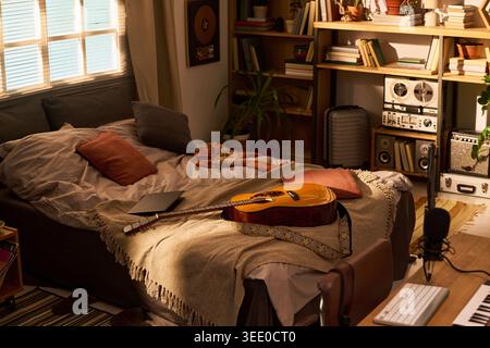 Wide angle shot of home music studio bedroom featuring acoustic guitar, laptop, microphone, keyboard, recording setup. Supporting songwriting, content creation, remote production marketing Stock Photo