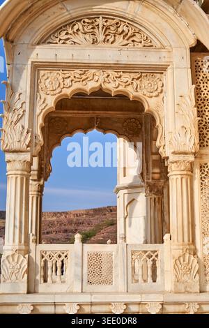 Close-up view of an ornately carved marble archway, showcasing intricate Rajasthani or Mughal architectural details. The creamy white stone features Stock Photo
