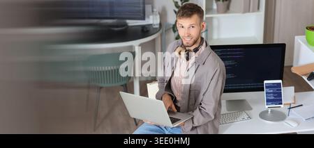 Young programmer working with laptop in office. Banner for design Stock Photo