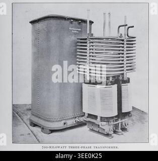 Large vintage three phase power transformer with heavy cooling coils and rugged metal tank, early 20th century industrial engineering investigation. From the Article A MODERN SWISS HYDRO-ELECTRIC POWER STATION. By Enrico Bignami. From The Engineering Magazine Devoted to Industrial Progress Volume XXXII October 1906 - March 1907 The Engineering Magazine Co Stock Photo