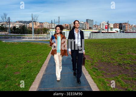 Two businesswomen walking on urban path discussing work Stock Photo