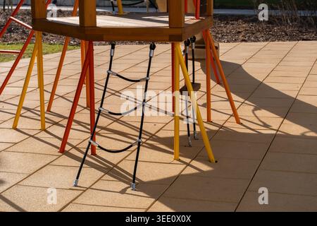 Closeup of rope ladder attached to colorful playground climbing structure on sunny outdoor playground. Modern child activity and recreational design c Stock Photo