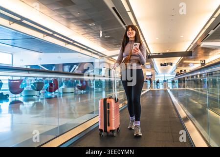 Woman traveling through airport terminal with luggage Stock Photo
