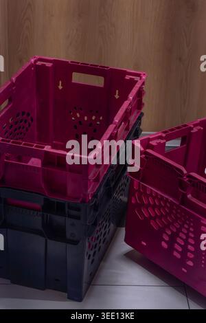 Empty plastic storage crates stacked indoors in retail, warehouse, or logistics environment. Commercial organization and inventory management concept Stock Photo
