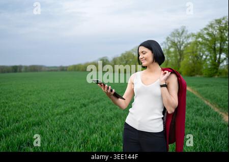 Woman using tablet while standing in green field outdoors Stock Photo
