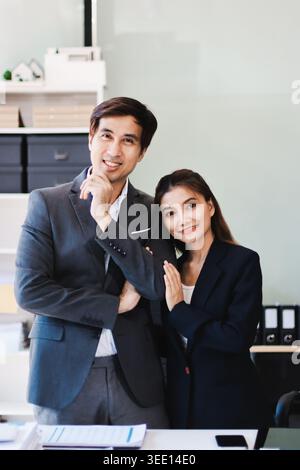Portrait of a happy Asian business couple standing together. Young professional man and woman smiling in studio. Corporate teamwork concept Stock Photo
