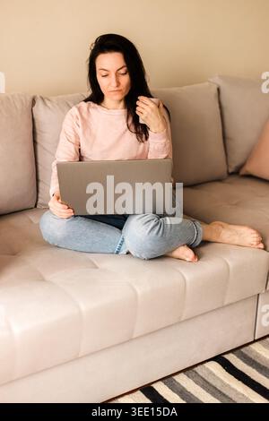 Young woman freelancer working on laptop at comfortable living room Stock Photo
