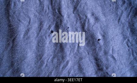 Worn out purple fabric texture with small holes and heavy wrinkles showing aged textile material for grunge design concepts. Stock Photo