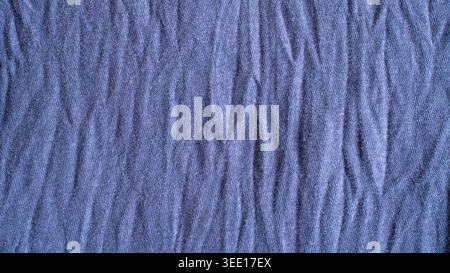 Detailed texture of crumpled purple fabric with vertical creases and shadows for textile industry background or fashion design. Stock Photo
