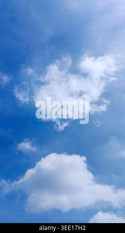 Puffy white clouds scattered across a bright blue sky on a clear sunny day Stock Photo