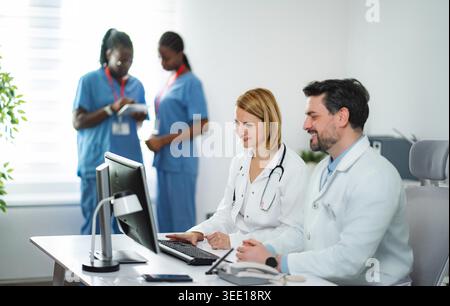 Doctors and nurses collaborating in medical office using a computer Stock Photo
