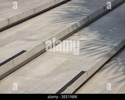 Close up view of gray stone steps outdoors displaying intricate palm frond shadows cast by sunlight creating tranquil and peaceful mood with geometric Stock Photo