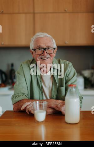 Smiling senior man drinking milk in kitchen. Stock Photo