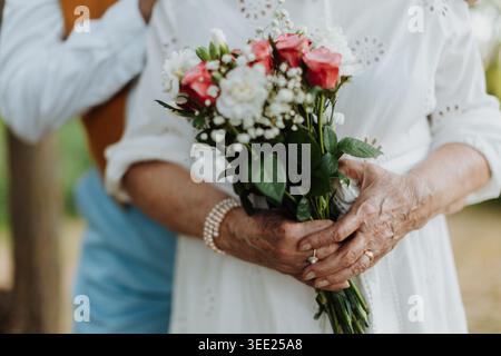 Close up of senior couple having marriage, bride holding bouquet. Stock Photo