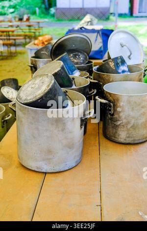 A row of large, well-used cooking pots sitting on a picnic table bench outside in Japan.  Stock Photo