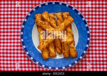 Cheese Twists all butter puff pastry with Gruyere cheese from M&S on plate on red and white checked gingham cloth Stock Photo