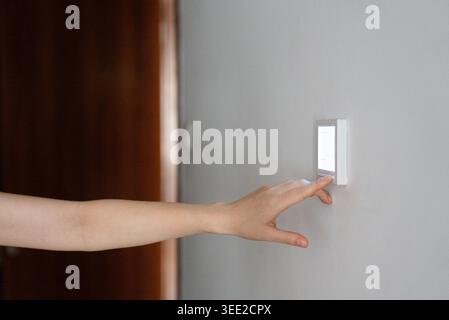 Close up of person switching light button on modern wall. Concept of electricity, energy usage, home automation and everyday household activity. Stock Photo