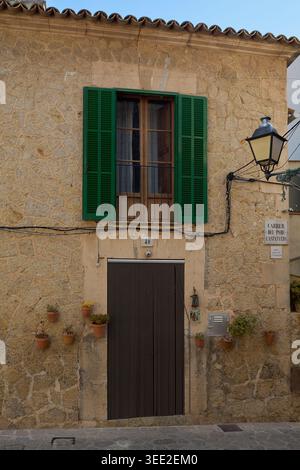 Traditional stone house facade on Carrer del Pare Castanyeda with green shutters and potted plants in the historic village of Valldemossa Mallorca Bal Stock Photo