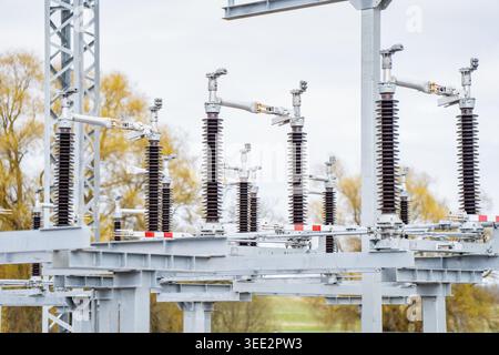 Electrical substation switchgear with rows of ceramic insulators on steel frame, showing power distribution and grid infrastructure work Stock Photo