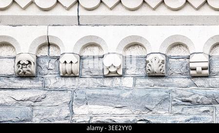 Close-up of University College stone facade with carved Romanesque ornamentation and decorative architectural patterns. Stock Photo