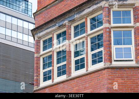 Close-up of Annesley Hall brick facade with large historic windows and contrasting modern building exterior. Stock Photo