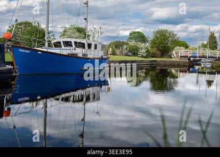 Nestled in the peaceful Fiddlers Ferry yacht haven, the Colvic Quest floats serenely on the calm waters of the Sankey canal, reflecting the lush green Stock Photo