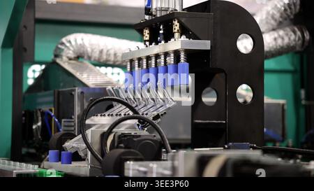 PET bottle machinery. Automated plastic bottle manufacturing machine operating on factory production line. Robot machine for bottle preform or forming Stock Photo