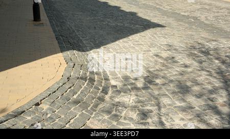 A winding cobblestone path meanders under the warm afternoon light creating shadows. Stock Photo