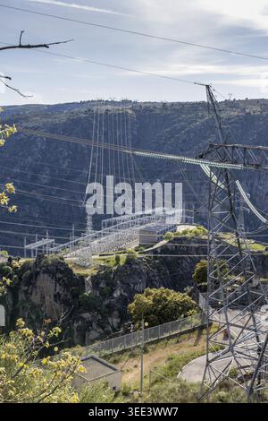 View of Aldeadavila II Electrical Substation with high-voltage power lines and transmission towers set against the rugged rocky cliffs of the Duero ri Stock Photo