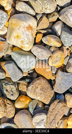 Close up shows many stones, assorted in colors and size. Textures vary from smooth to rough. Natural lighting. Represents grounding, stability, and na Stock Photo