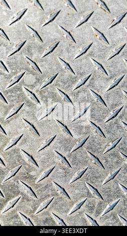 Macro shot showcases industrial metal surface. Features repeating raised diamond pattern, creating non slip texture. Silver color, diffused lighting h Stock Photo