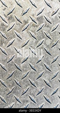 Metal diamond plate background. Industrial, rough texture with repeating diamond pattern. Silver metallic tones, grunge surface, and angled highlights Stock Photo