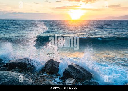 Powerful sea waves crashing on rocks during sunset in Greece Stock Photo