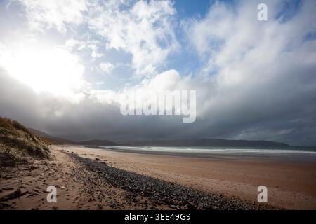 Muiríoch Beach, Dingle, Kerry, Ireland. Wide strand with intensive cloudy sky, Storm clouds and sunlight over a deserted sandy beach with sand dunes. Stock Photo