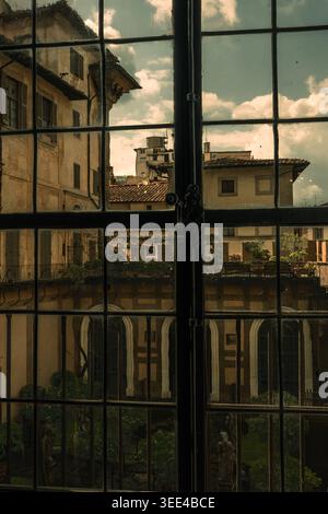 A close-up view through a gridded windowpane capturing the reflections of historic Florentine buildings and a cloudy sky. The image features tradition Stock Photo