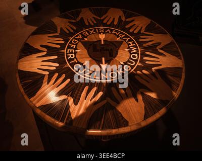 High-angle, close-up shot of a meticulously crafted wooden tabletop, showcasing detailed marquetry. The surface features light-toned hand silhouettes Stock Photo