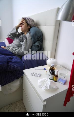 Side view of woman in bed with medicine, indicating a state of discomfort and illness, a cold Stock Photo