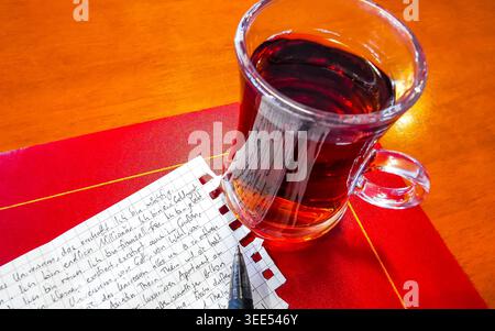 Turkish black tea chai in a glass on a restaurant table with a notepad and a pen in Patong Beach Kathu District Phuket Island Province Southern Thaila Stock Photo