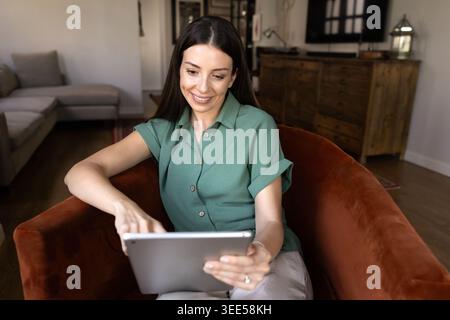 Adult 30s woman working remotely from home using tablet Stock Photo