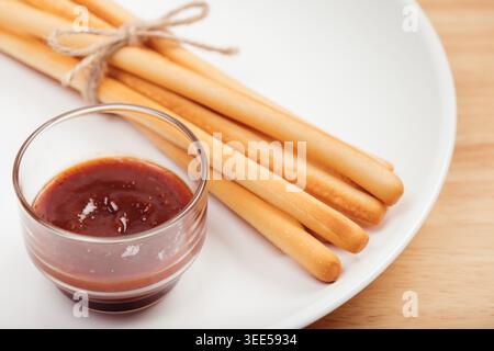 pack of breadsticks with ketchup dipping sauce in white dish on wood table Stock Photo