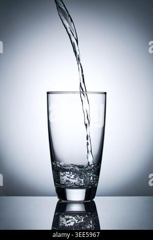 puring refreshment freshness drinking water on clean transperence glass in studio back light Stock Photo