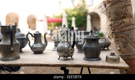 Flea antiques market in Nice, France, at Franciscan monastery of Cimiez. Old metal teapots, coffee makers on table. Vintage exhibition for sale. Stock Photo
