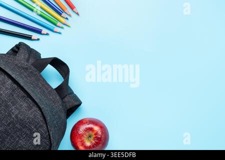 school backpack apple and colored pencils on blue background copy space back to school concept Stock Photo
